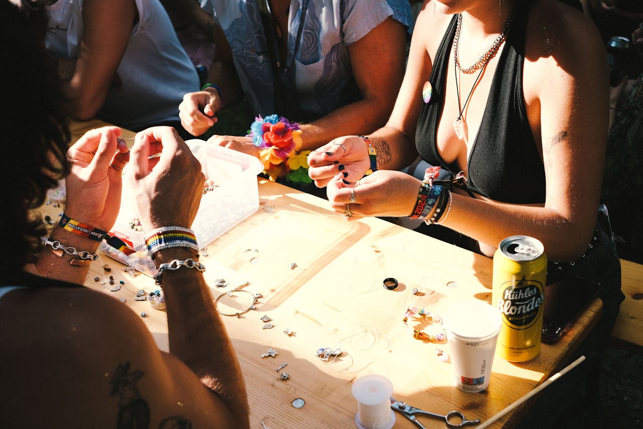 People making jewelry bracelets at a vibrant outdoor craft event.